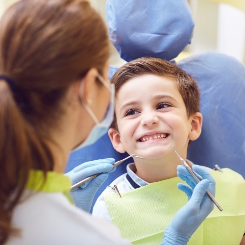 Young boy in dental chair grinning at dental team member