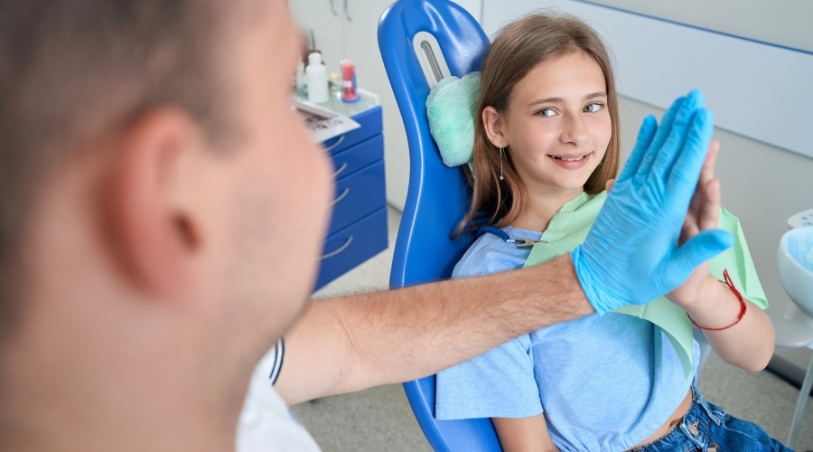 Young girl giving high five to board certified pediatric dentist in Southampton