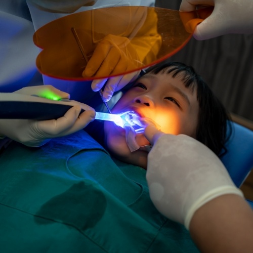 Child in dental chair having fluoride applied to their teeth