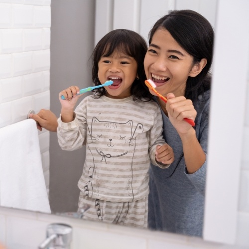 Mother and daughter brushing their teeth together