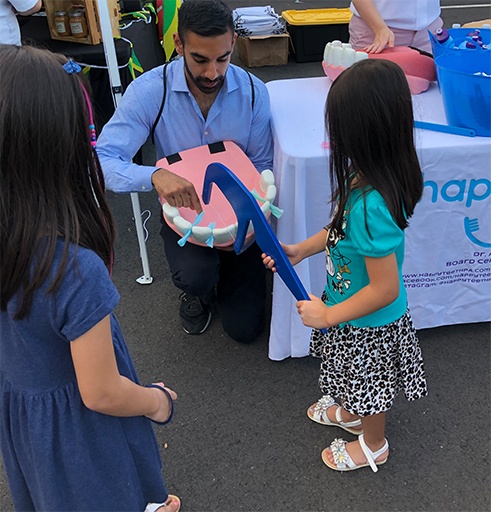 Pediatric dentist playing a game with kids at a Southampton community event