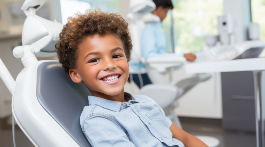 Young boy in denim shirt smiling in dental chair