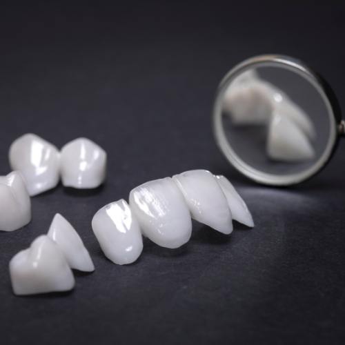 Several white dental crowns on table next to dental mirrors