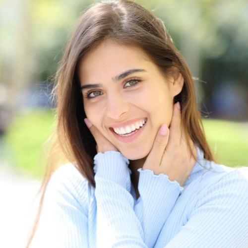 Woman in light blue blouse smiling outdoors