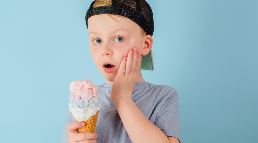 Boy with ice cream cone holding his cheek in pain needing emergency kids dentist in Southampton