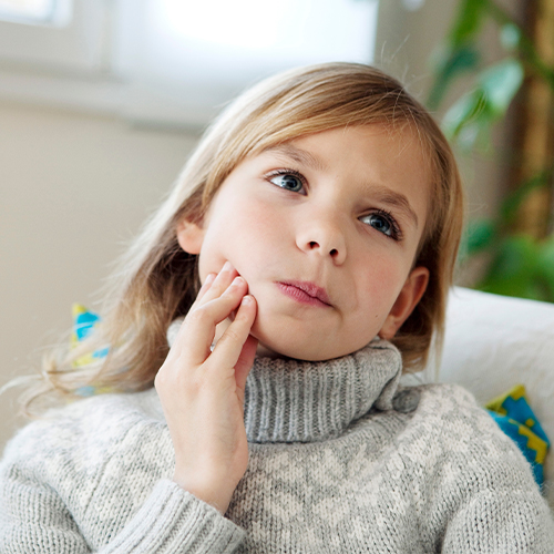 Young girl holding her cheek in pain before tooth extraction in Southampton