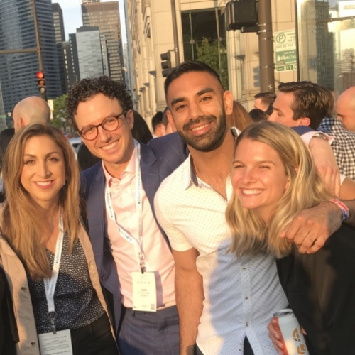 Doctor Singh smiling with three other people at sunset with city skyline in background