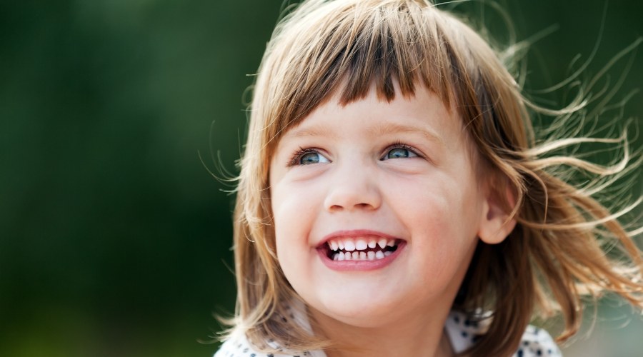 Young girl smiling outdoors after restorative dentistry in Southampton