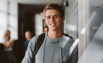 Teen boy with backpack leaning against wall of lockers