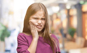 Little girl with toothache holding her cheek