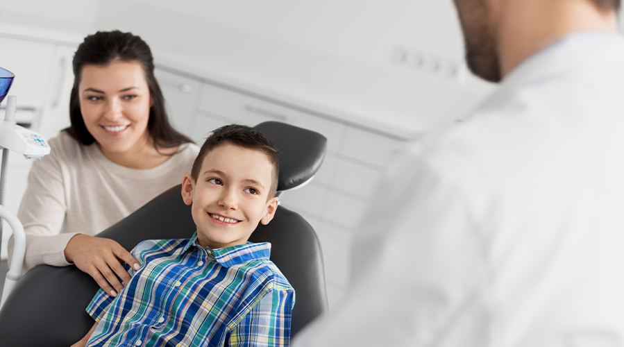 Young boy in dental chair smiling at his pediatric dentist in Southampton